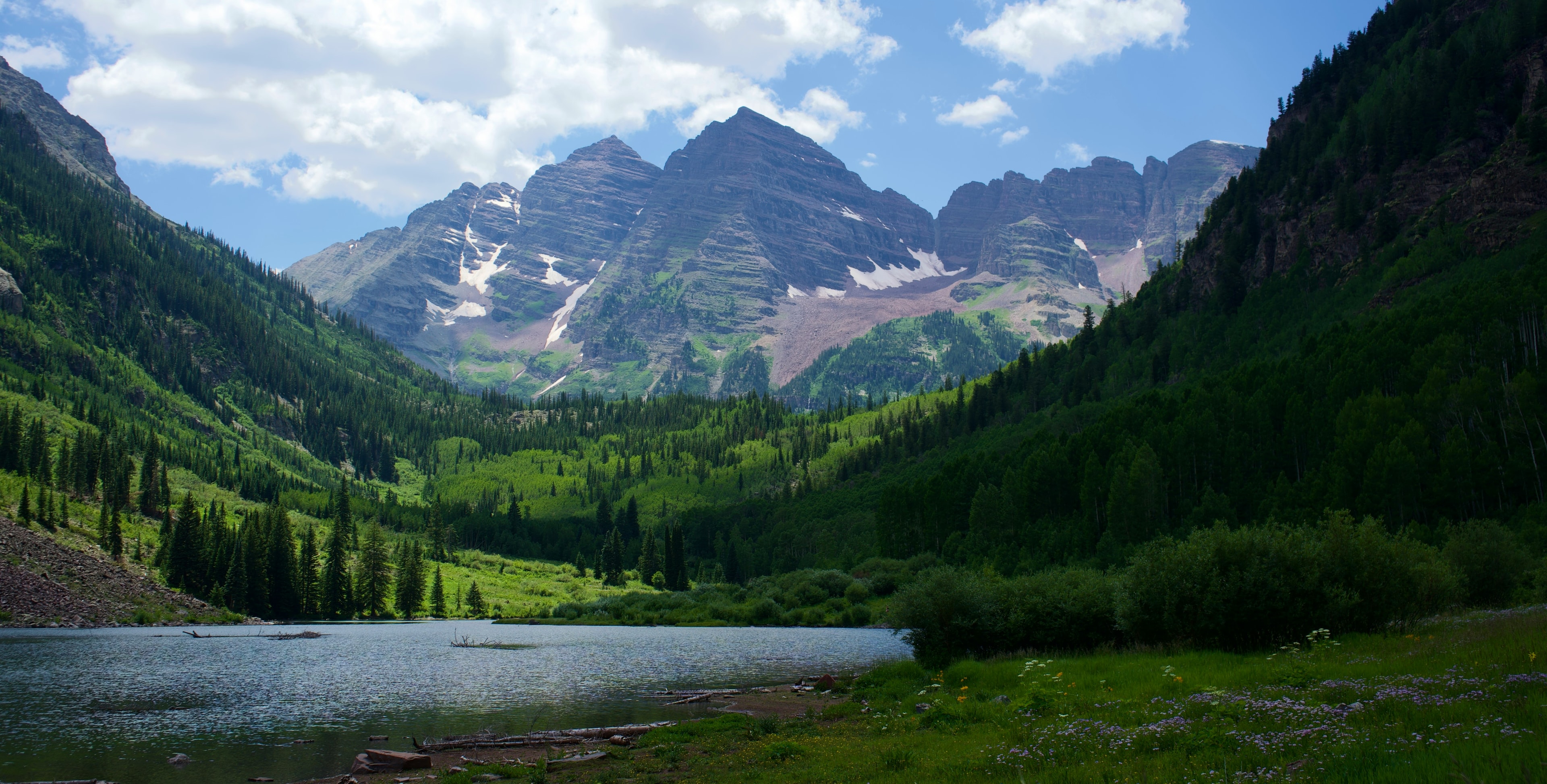 Maroon Bells, Colorado — snow-capped peaks above a green summer valley and Maroon Lake